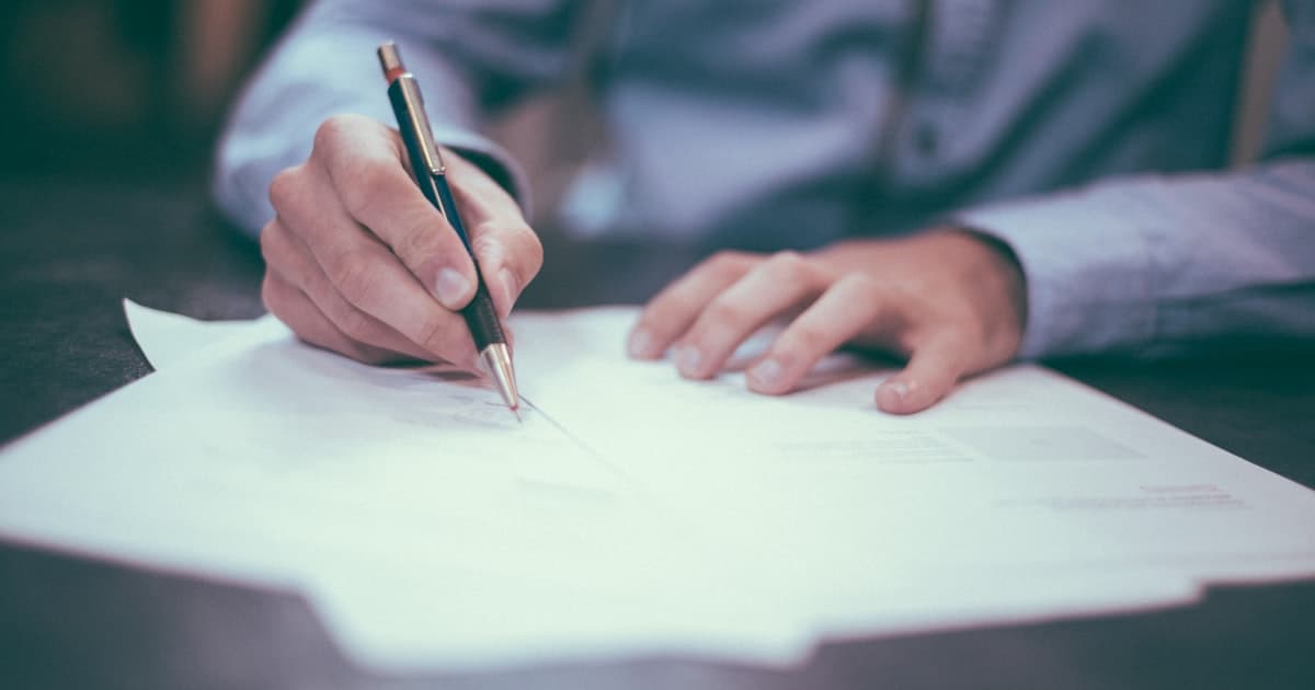 Person signing mortgage documents at desk